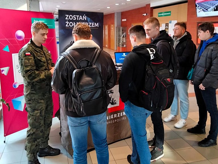 Grupa studentów stoi przy żołnierzu