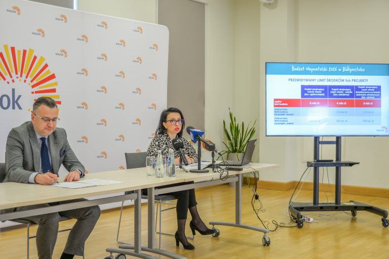 Dwie osoby przy stoliku mówią do mikrofonu.