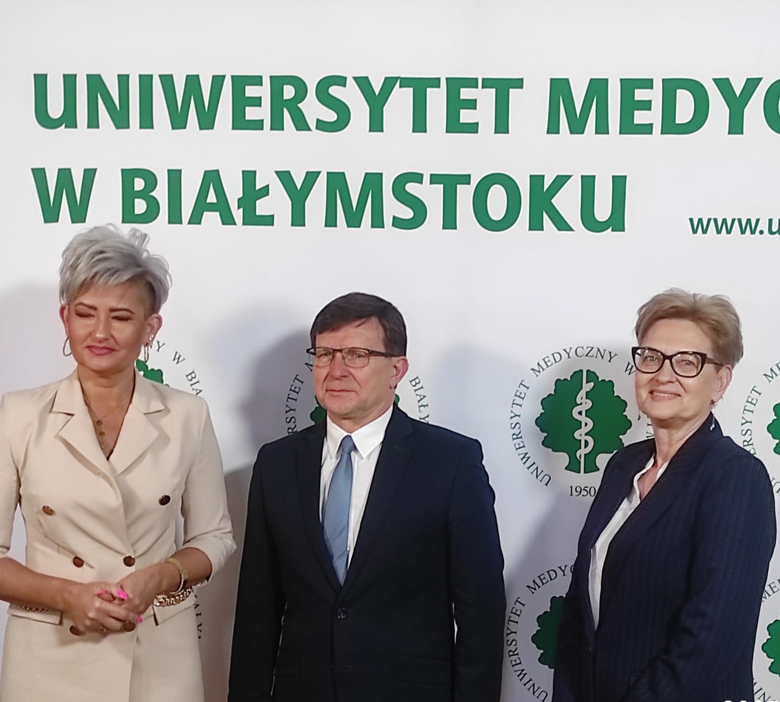 Uczestnicy konferencji pozują na ściance do zdjęć UMB.