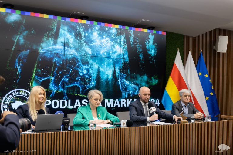 Cztery osoby siedzą za stołem na konferencji prasowej.