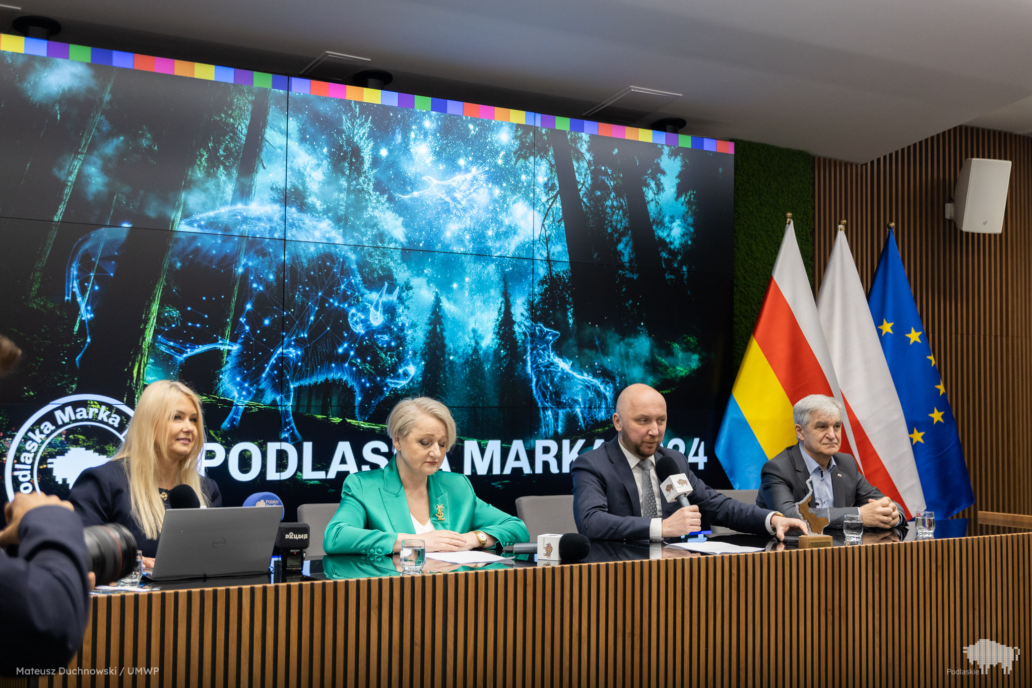 Cztery osoby siedzą za stołem na konferencji prasowej.