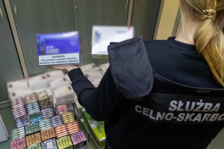 Funkcjonariuszka KAS, trzyma w dłoni zabezpieczone wyroby tytoniowe.