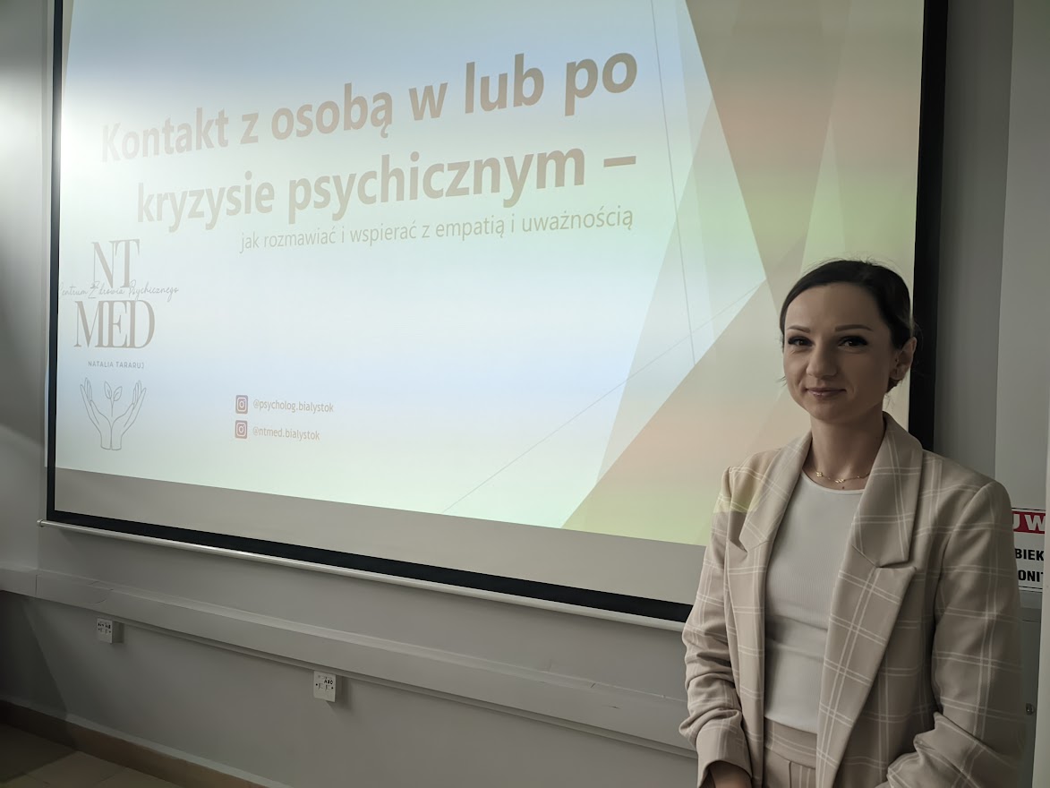 kobieta na tle tablicy z wykladem na temat zdrowia psychicznego ubrana w jasny garnitur