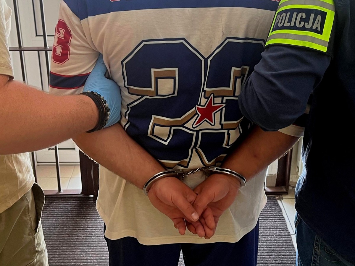 Mężczyzna w kajdankach trzymany przez funkcjonariuszy policji po zatrzymaniu w centrum Białegostoku za groźby karalne i zniszczenie mienia