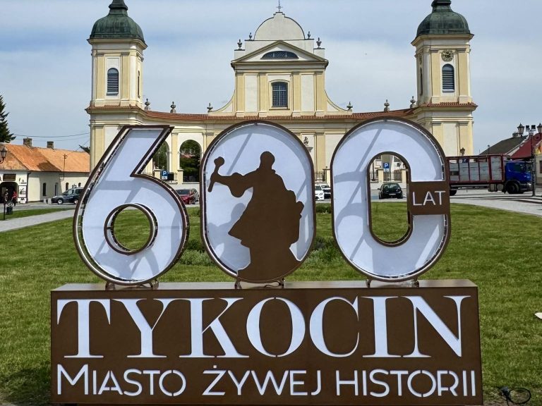 widok na kosciol w tykocinie na pierwszym planie napis tykocin 600 lat miasto zywej historii