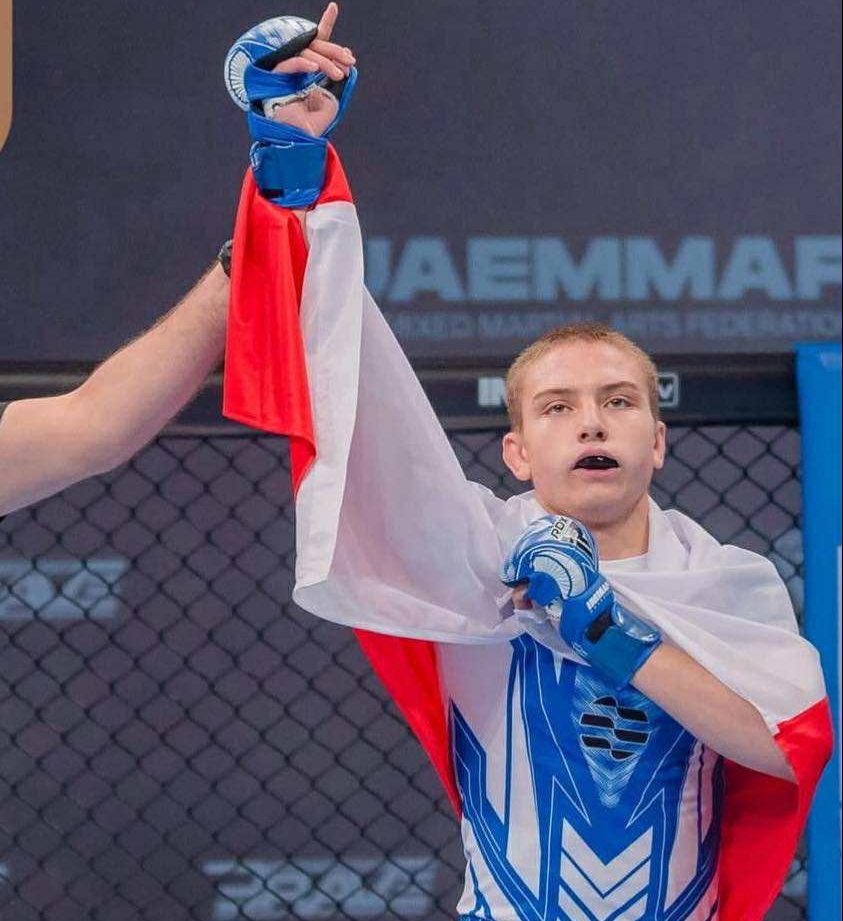 Wojtek wyszyński po wygranej walce z ręką w górze i fladze Polski na plecach