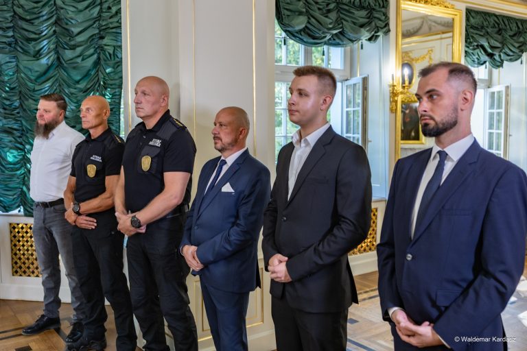 Mężczyźni stoją w eleganckiej sali.