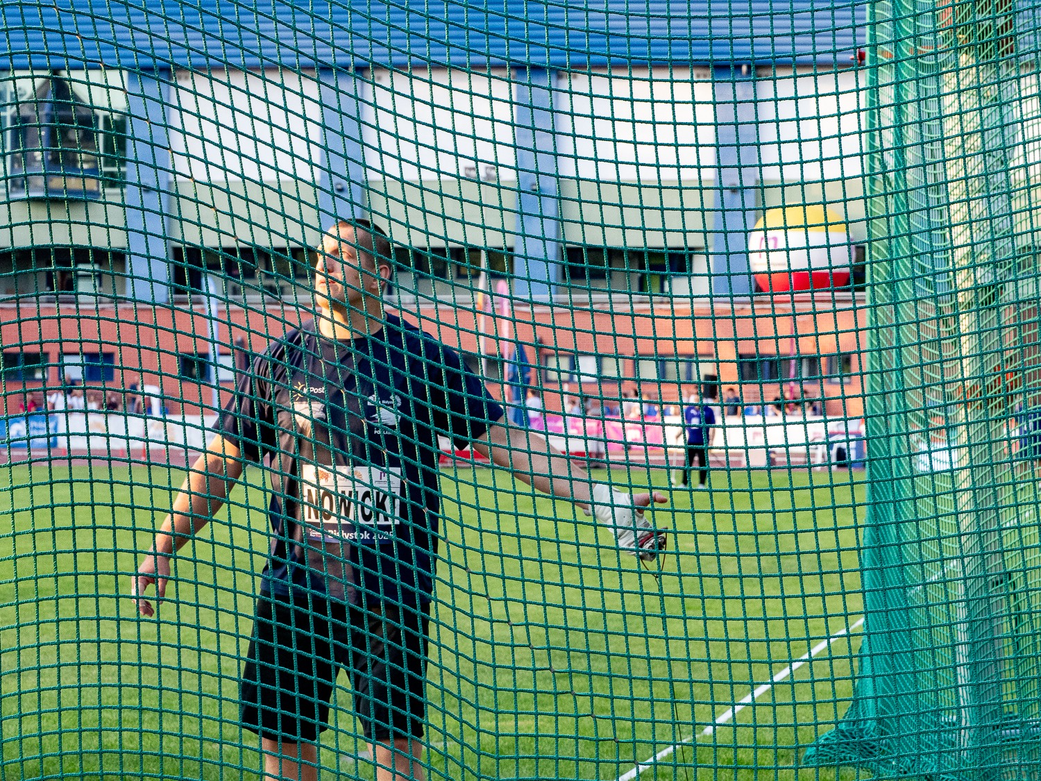 Mężczyzna na stadionie rzuca młotem.