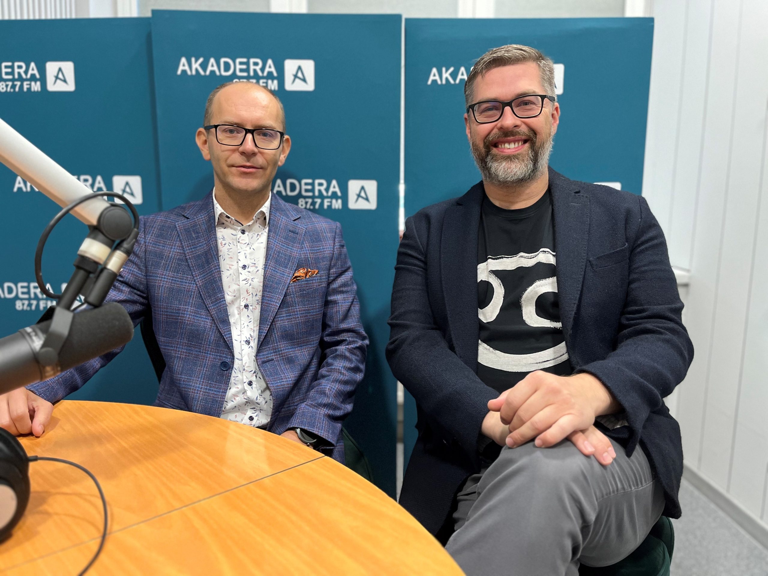 Dwaj mężczyźni – dr Łukasz Nazarko i Marcin Rodzianko – siedzą w studiu Radia Akadera przy stole z mikrofonem. W tle niebieskie ścianki z logo AKADERA 87.7 FM.