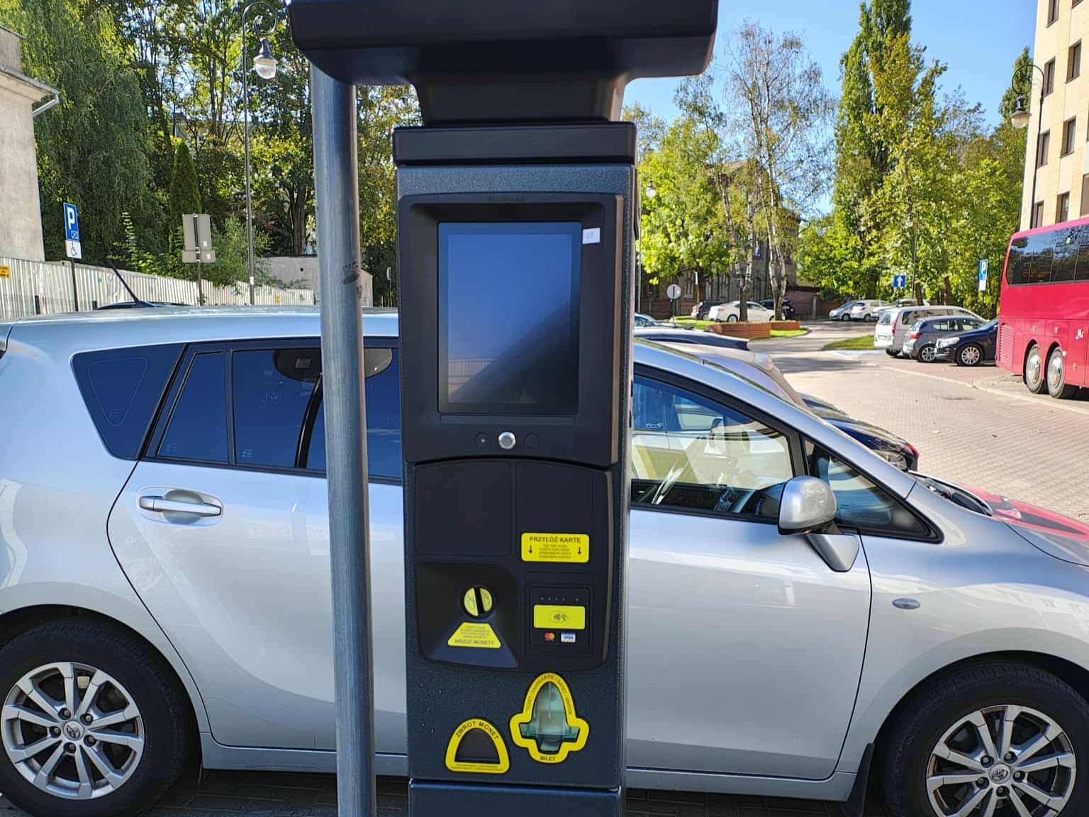 Nowy parkomat w Strefie Płatnego Parkowania w Białymstoku z funkcją płatności kartą i BLIK-iem. W tle zaparkowane samochody na miejskim parkingu.