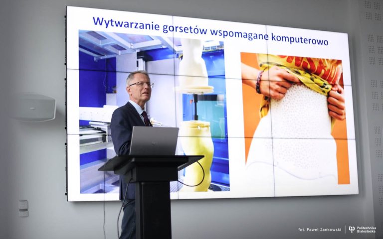 Dr hab. inż. Piotr Mrozek, prof. Politechniki Białostockiej, podczas prezentacji innowacyjnej metody komputerowego projektowania gorsetów ortopedycznych; w tle slajd pokazujący proces wytwarzania gorsetów i przykład ich zastosowania.