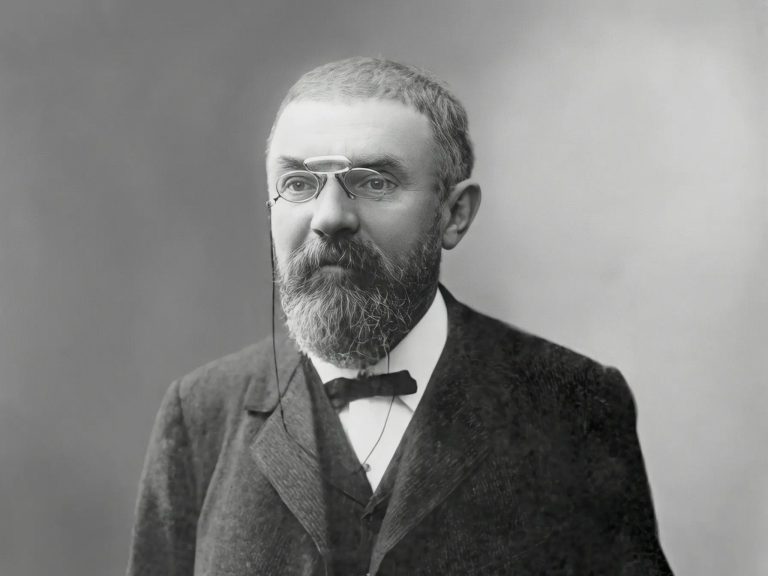 Czarno-biały portret Henriego Poincarégo w formalnym stroju, z brodą i okularami pince-nez, fotografia z 1913 roku, wykonana przed 1923 rokiem.
