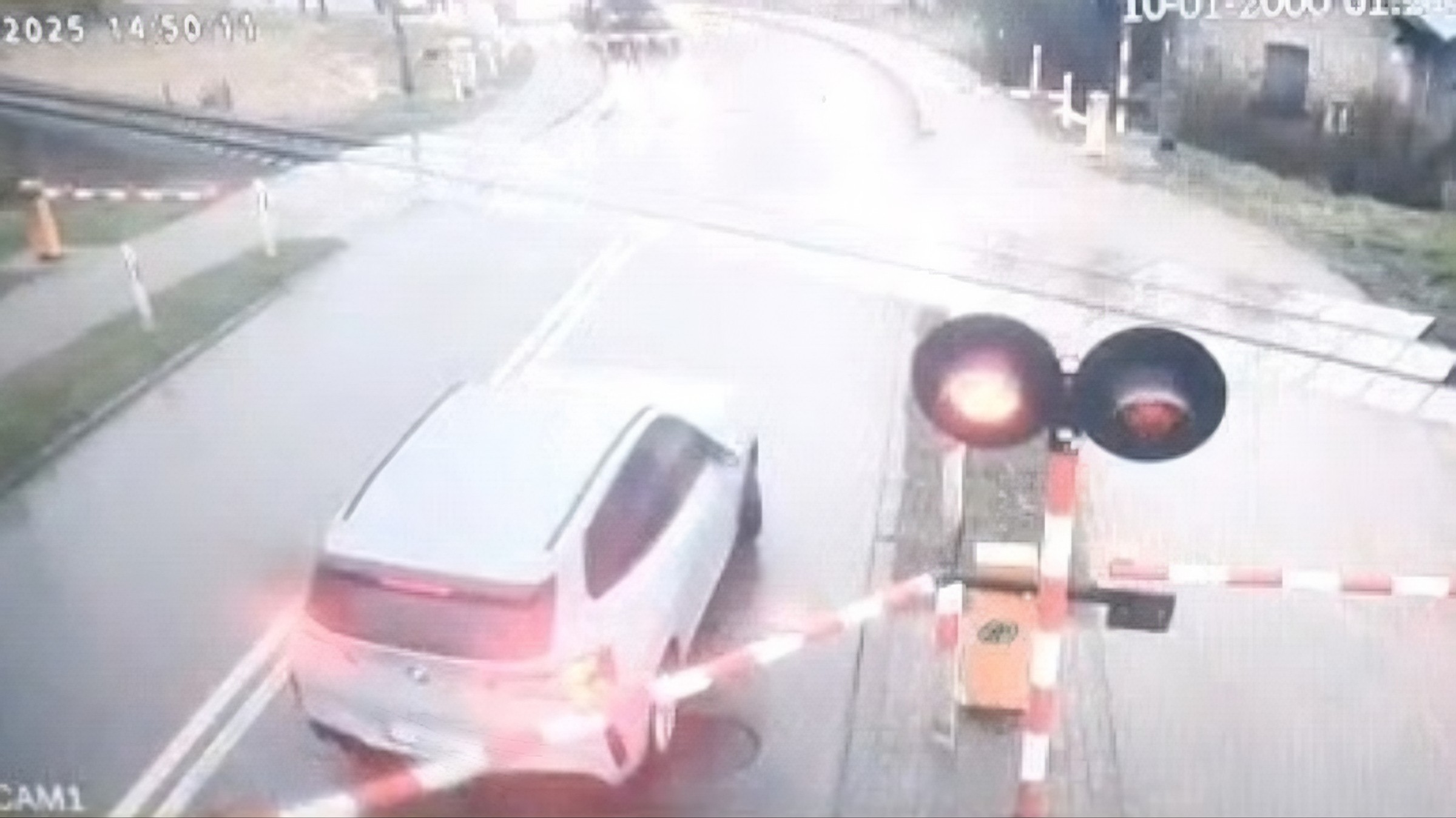 Samochód osobowy marki BMW wjeżdża na przejazd kolejowy w Hajnówce mimo włączonych sygnałów świetlnych i opuszczonych zapór, kadr z monitoringu.